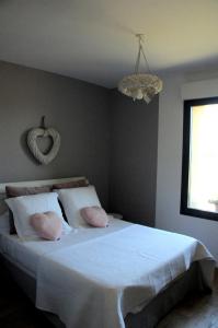 1 dormitorio con cama blanca y almohadas rosas en MAS CAMBEL, en Brouilla