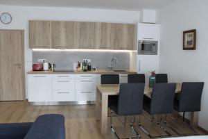kuchnia z drewnianym stołem i czarnymi krzesłami w obiekcie Apartmán Lipno G11 w mieście Frymburk
