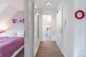 オストゼーバート・ニーンハーゲンにあるHaus Passat - Ferienwohnungenの白い壁のベッドルーム(紫色のベッド1台付)