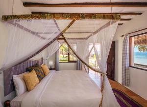 a bedroom with a bed with a canopy at Filao Beach by Sansi in Uroa