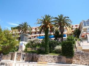 a retaining wall with palm trees in front of a building at Hotel Aurora in Podgora