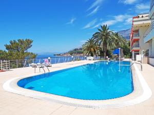 a large blue swimming pool with a view of the ocean at Hotel Aurora in Podgora
