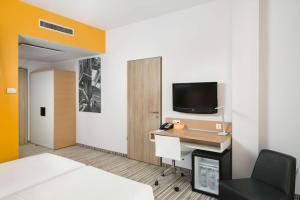 a room with a bed and a desk and a tv at Park Inn By Radisson Budapest in Budapest