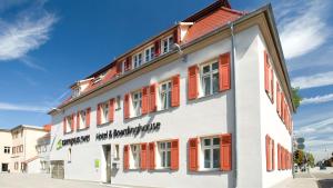 un edificio blanco con persianas naranjas. en campuszwei - Hotel & Boardinghouse, en Ludwigsburg