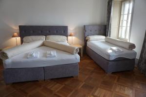 a bedroom with two beds and a couch and two windows at Villa Pochon in Gunten