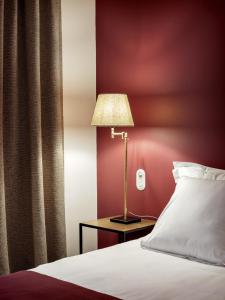 a bed with a lamp next to a red wall at New Hotel Le Voltaire in Paris