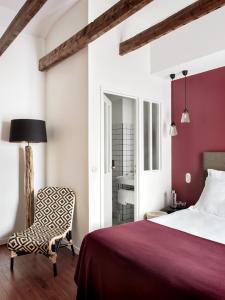 a bedroom with a red bed and a chair at New Hotel Le Voltaire in Paris
