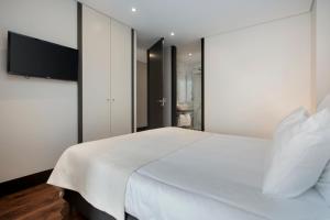 sypialnia z białym łóżkiem i telewizorem z płaskim ekranem w obiekcie Live in Porto - 68 Regras w Porto
