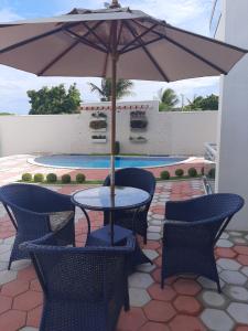 uma mesa e cadeiras com um guarda-sol num pátio em Terraço Hotel em Lagoinha