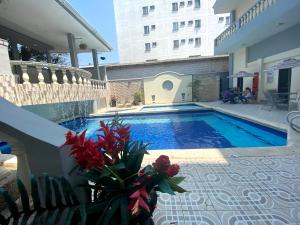 a swimming pool with flowers on the side of a building at Hotel Puerta de Oro in Barranquilla