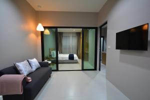 a living room with a couch and a flat screen tv at The Grey House Palai Phuket in Chalong 
