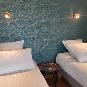 a bedroom with two beds and a wall with a spiderweb wallpaper at La Clé du Puy in Cabariot