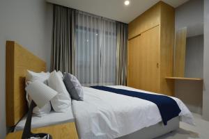 a bedroom with a white bed and a window at The Grey House Palai Phuket in Chalong 