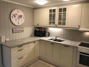 a kitchen with white cabinets and a sink and a clock at Notodden Sentrum Apartment NO 3 in Notodden