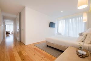 a white bedroom with a bed and a living room at Aqua - Pópulo Eco Village in Ponta Delgada