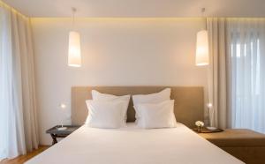 a bedroom with a large white bed with two pillows at Aqua - Pópulo Eco Village in Ponta Delgada
