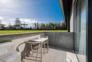 a patio with two chairs and a table on a wall at Aqua - Pópulo Eco Village in Ponta Delgada
