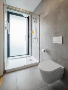 a bathroom with a shower and a toilet and a window at Aqua - Pópulo Eco Village in Ponta Delgada