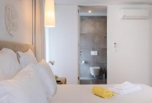 a white bed with a yellow towel on top of it at Aqua - Pópulo Eco Village in Ponta Delgada
