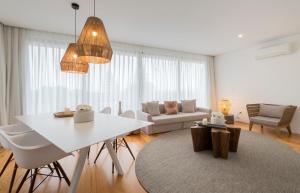 a white living room with a white table and chairs at Aqua - Pópulo Eco Village in Ponta Delgada