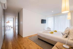 a white bedroom with a bed and a living room at Aqua - Pópulo Eco Village in Ponta Delgada