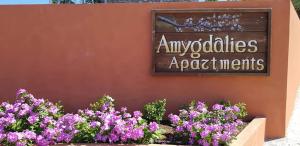 a sign on a wall with purple flowers at Amigdalies in Myrina