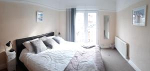 a bedroom with a bed with white sheets and a window at Marine Lake apartment in West Kirby