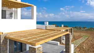 a house with a wooden deck next to the ocean at Vastblue of Paros in Ambelas