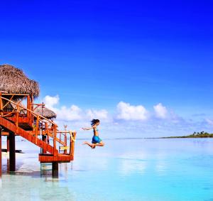 Una ragazza che salta da un molo in acqua di Aitutaki Lagoon Private Island Resort (Adults Only) ad Arutanga