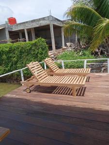 2 chaises en bois assises sur une terrasse en bois dans l'établissement Blue Coral Homestay, à Karimunjawa