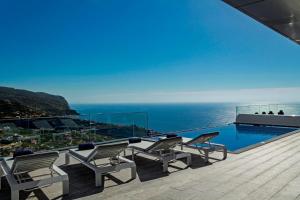 un balcón con sillas, una piscina y el océano en OurMadeira - Seacrest, premium luxury, en Ponta do Sol