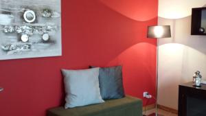a room with a red wall with a pillow and a lamp at Next University in Aveiro