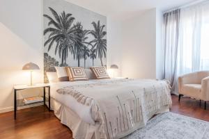 ein weißes Schlafzimmer mit einem großen Bett und einem Stuhl in der Unterkunft Tu Escapada Urbana - Plaza de Castilla III, Diseño y Localización in Madrid + 32 Fotos