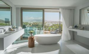 a bathroom with a large tub and large windows at Four Seasons Astir Palace Hotel Athens in Athens