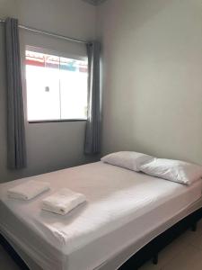 a bed with two white pillows and a window at Casa villa boa in Pirenópolis +44 photos