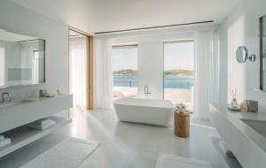a white bathroom with a tub and a large window at Four Seasons Astir Palace Hotel Athens in Athens