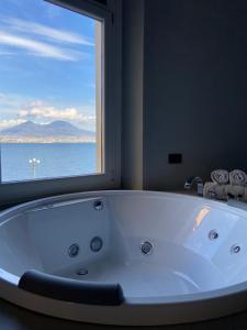 a large white bath tub in a bathroom with a window at Relais sul Mare Boutique Hotel in Naples