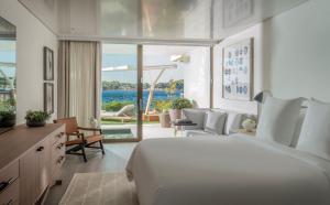 a bedroom with a white bed and a view of the ocean at Four Seasons Astir Palace Hotel Athens in Athens
