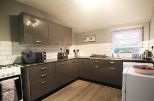 cocina con armarios grises y microondas en Panton Road - Modern Classic Terrace, en Chester