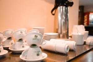 a kitchen counter filled with white cups and white utensils at Nacional Inn Campinas Trevo in Campinas