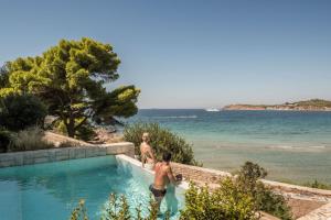 two men in a swimming pool next to the ocean at Four Seasons Astir Palace Hotel Athens in Athens