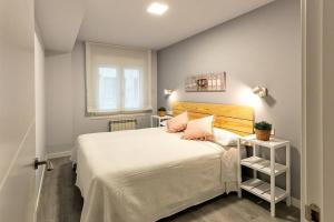 a bedroom with a white bed with pink pillows at VIVE BURGOS VUT-09 200 in Burgos