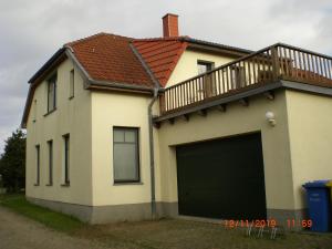 a white house with a garage door and a balcony at Ferienhaus Weitblick in Börgerende-Rethwisch