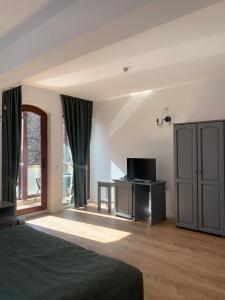 a bedroom with a bed and a tv and a window at Pension Casa Vanatorilor in Băile Olăneşti