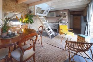 a living room with a wooden table and a kitchen at Le petit gîte cosy de Kerigou avec vue mer et plage in Saint-Pol-de-Léon