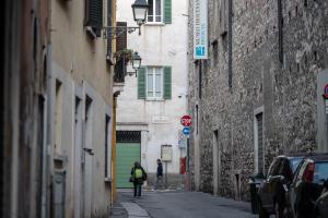 two people walking down a street in an alley at LUOGO COMUNE Ostello in Brescia