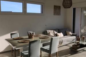 a dining room with a table and chairs and a couch at APPT NEUF haut de gamme, Terrasse, Sud Montpellier in Pérols