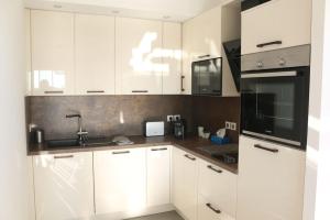 a kitchen with white cabinets and a black appliance at APPT NEUF haut de gamme, Terrasse, Sud Montpellier in Pérols +11 photos