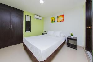 a bedroom with a large white bed and green walls at Hotel Avexi Suites By GEH Suites in Cartagena de Indias