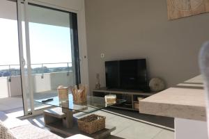 een woonkamer met een glazen tafel en een televisie bij APPT NEUF haut de gamme, Terrasse, Sud Montpellier in Pérols
